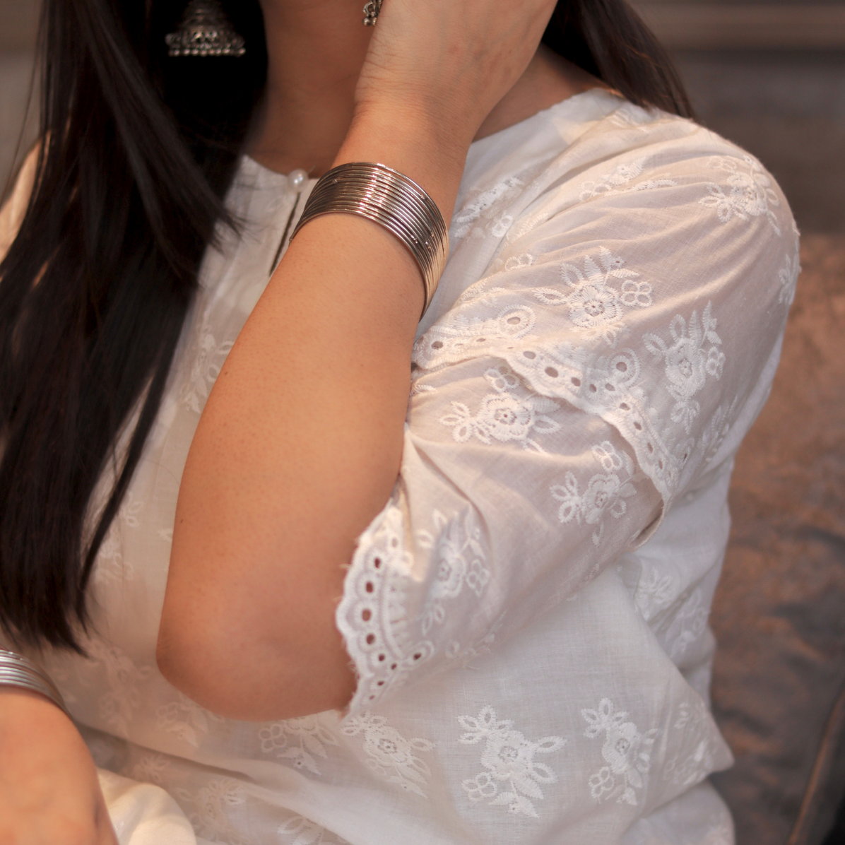 Close-up of a person wearing a white embroidered outfit with a blurred background